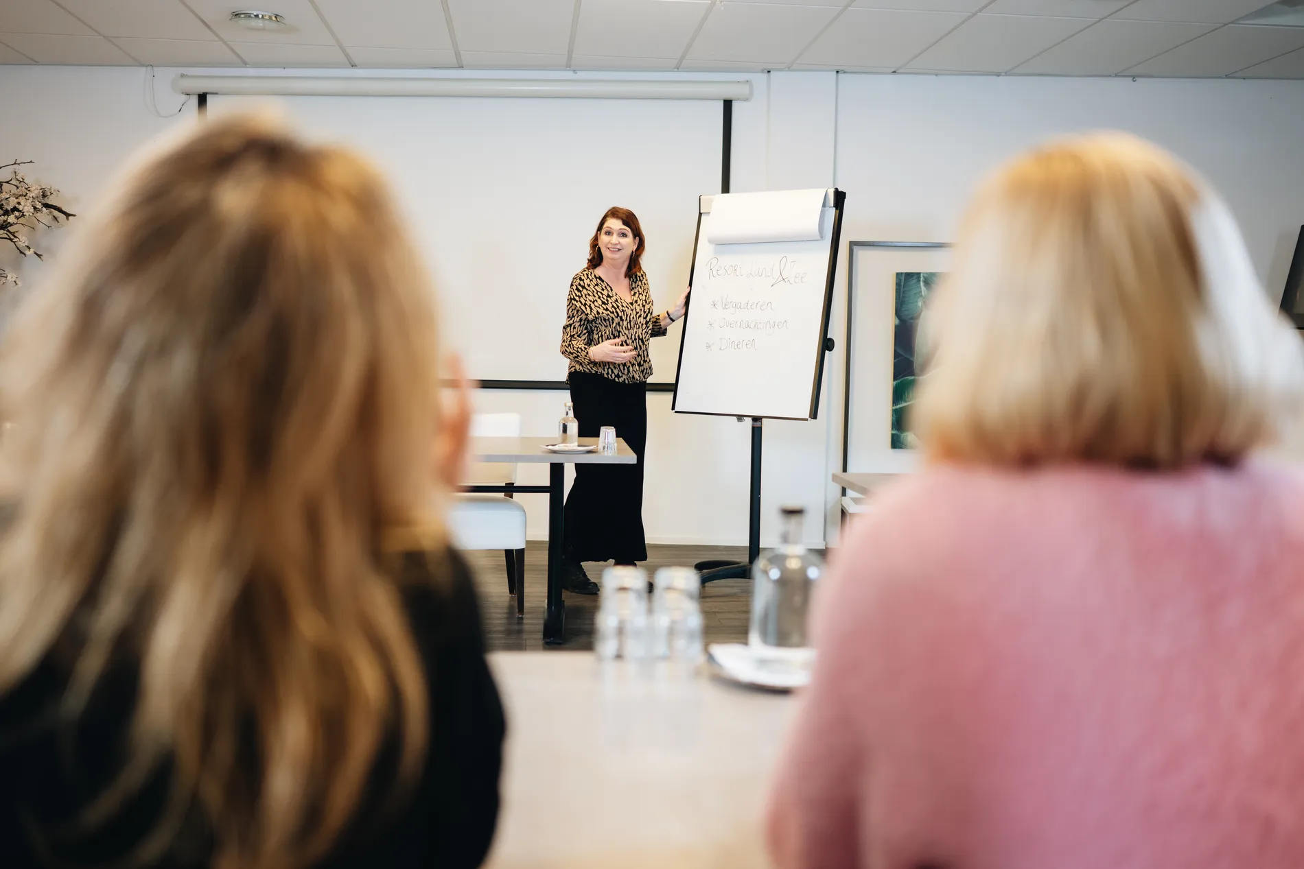 Presentatie in de moderne vergaderruimte van Resort Land & Zee met focus op vergaderen, overnachtingen en dineren.